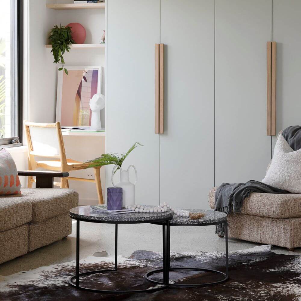 Modern living room with textured beige sofas, round marble coffee tables, built-in shelving, and minimalist cabinetry – Ren Studio.
