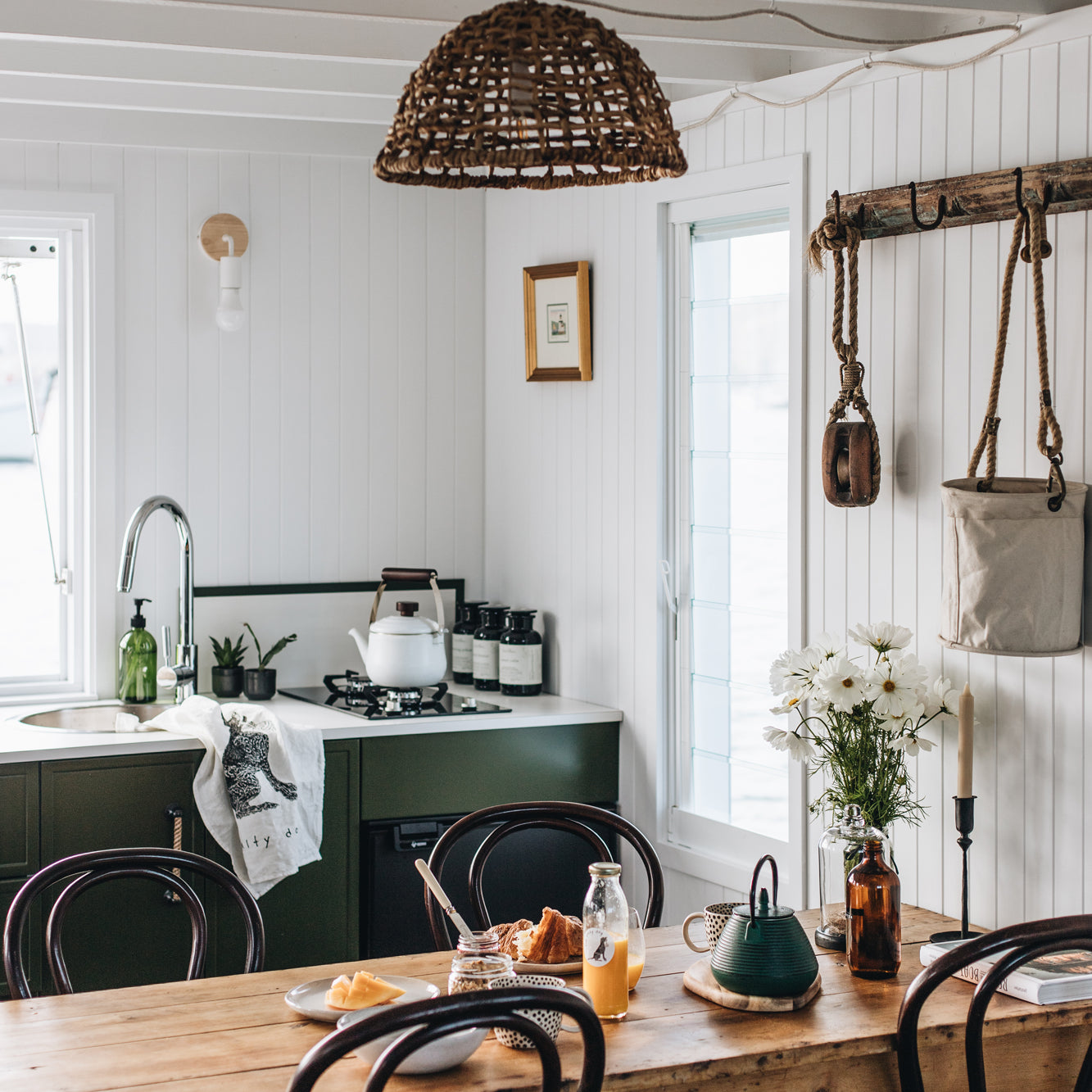Cozy kitchen with green cabinets, wooden dining table, and rustic decor.